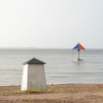 Simhus, strand, hav och en karusell i vattnet.