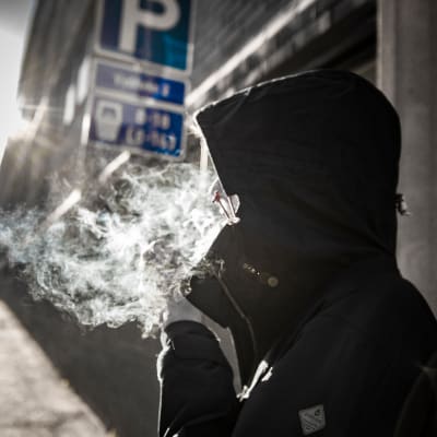 Ihminen polttaa kannabista tai tupakkaa kadulla