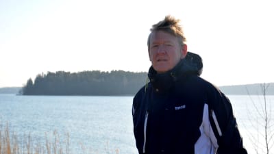man står vid vattnet och i bakgrunden syns en ö.