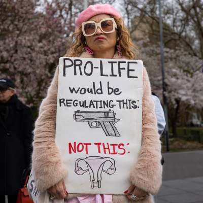 En kvinna håller upp en skylt där det står att pro-life borde handla om att reglera pistoler, inte abort.