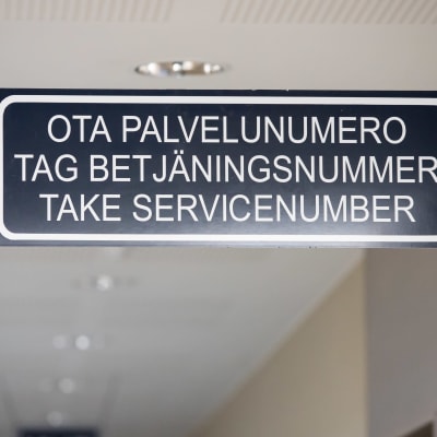 Ota palvelunuemro kyltti toimiston asiakaspalvelun katossa suomeksi, ruotsiksi ja englanniksi. 