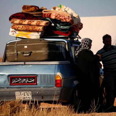 Syyrialaisia pakolaisia seisomassa täyteen pakatun autonsa vieressä lähellä Jordanian rajaa.