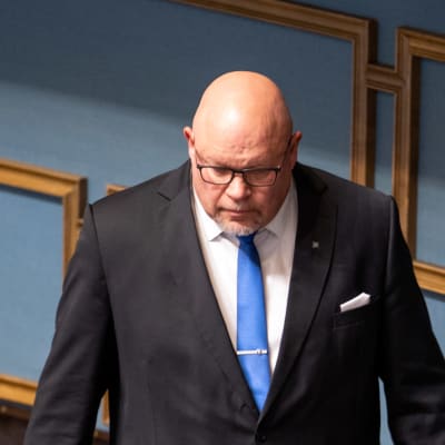 Ano Turtiainen i kostym i riksdagens plenisal.