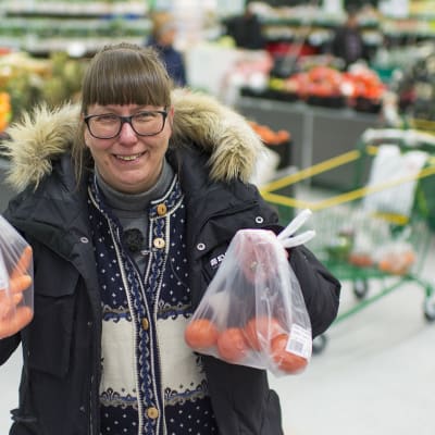 Hannele Kaskinen pitelee kahta hedelmäpussia kaupassa.