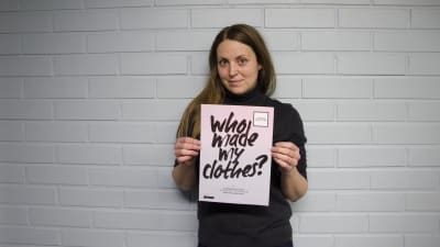 Sarah Jussila från Fashion Revolution håller upp en skylt där det står "Who made my clothes?"