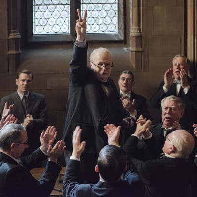 Winston Churchill (Gary Oldman) går segertecknet omringad av en massa människor.