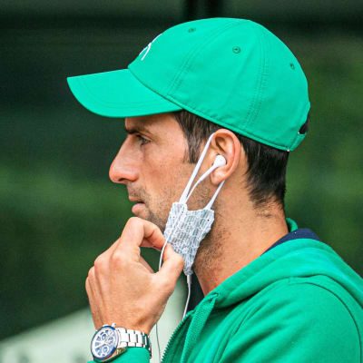 Novak Djokovic med munskyddet hängande under hakan.