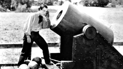 Buster Keaton seisoo valtavan mörssärin suulla ja kuulostelee, kuuluuko putkesta jotain. Kuva elokuvasta Kenraali.