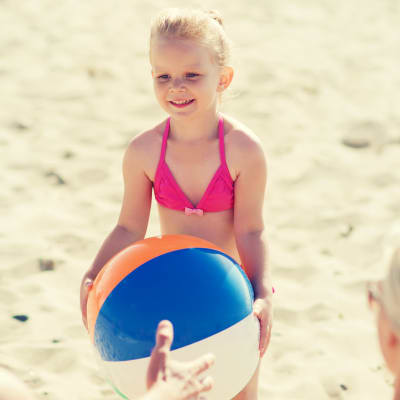 En flicka leker på stranden med sina föräldrar. 