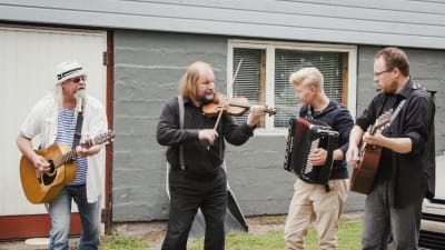 Neljä muusikkoa esiintyy La Kala -oopperatalon edustalla, kaksi kitaristia, viulunsoittaja, harmonikansoittaja