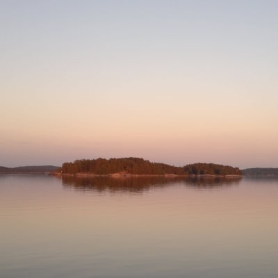 Sen kväll i Åbolands skärgård, med ett rosa sken över öar och hav.