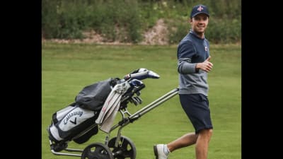 Golfaren Rasmus Karlsson drar en golfkärra efter sig.