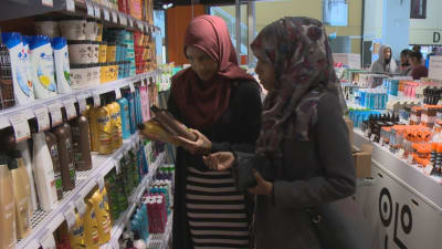 Två unga kvinnor i hijab tittar på schampoo i en affär.