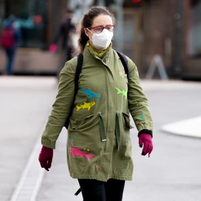 En kvinna med ansiktsskydd på går ute på stan.