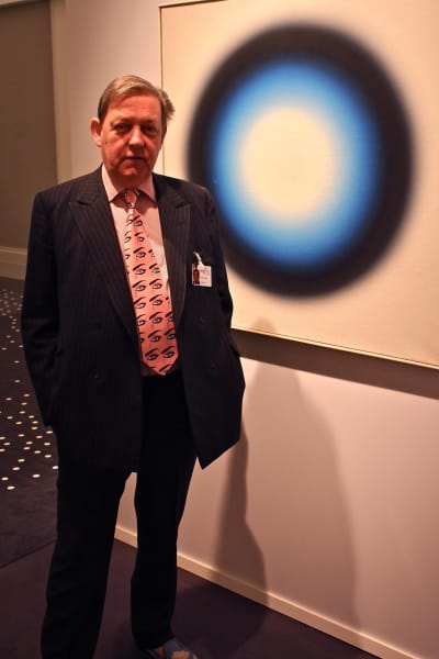 James Mayor poserar bredvid ett  Op-art konstverk från 1963 av polacken Wojciech Fangor. Lägg märke till Mayors kravatt.