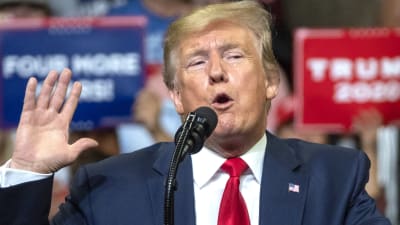 Donald Trump håller upp ena handen och håller ett tal inför publik i Orlando.