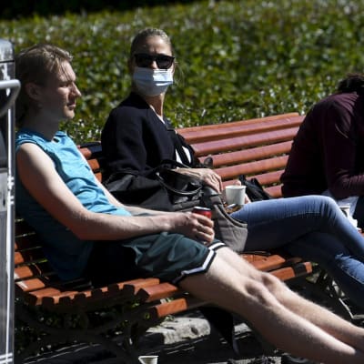 Bänkar fyllda med folk i Esplanadparken i Helsingfors.