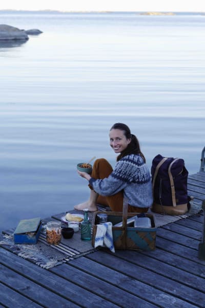 en kvinna sitter på en brygga vid havet och har mat och kärl runtom sig