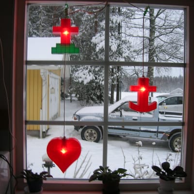 Anneli Lehtosen ikkunassa roikkuvat punaiset jouluvalot joissa risti, sydän ja ankkuri
