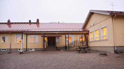 En gul träbyggnad med rött tak. Bilden är tagen ganska nära huset så att man ser huvudingången.