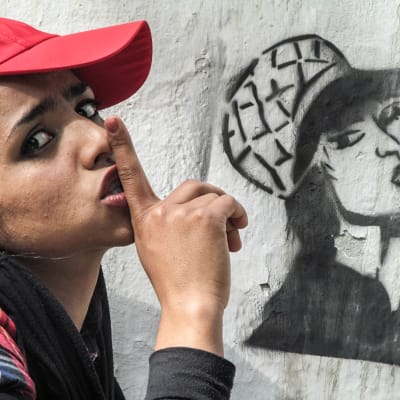 Sonita poserar framför en vägg med graffiti.