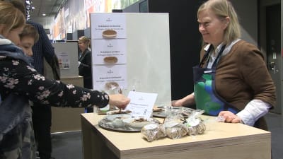 En kvinna säljer finländska knäckebröd på en mässa.