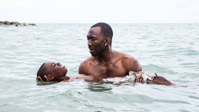 Chiron (Alex R. Hibbert) försöker lära sig att flyta i vattnet medan Juan (Mahershala Ali) håller i honom.