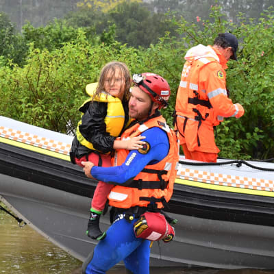 En man bär iland ett barn från en båt. 