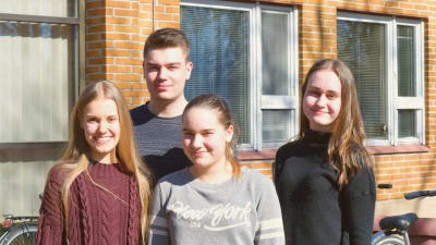 Fyra gymnasieelever ståt ute på en skolgård.