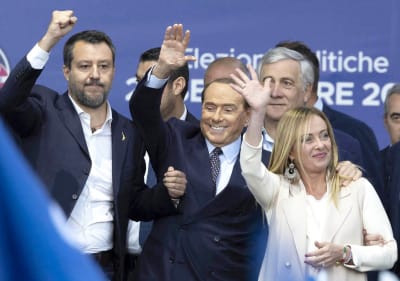 Matteo Salvini, Silvio Berlusconi och Giorgia Meloni vinkar på en scen.