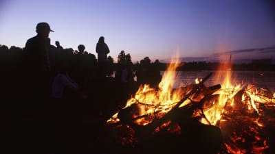 Människor tittar på en midsommarbrasa
