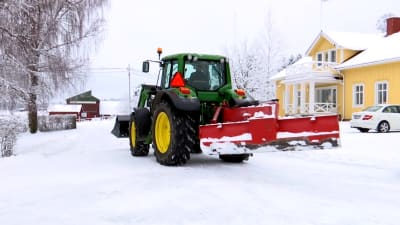 En traktor med plog i snöigt landskap. 