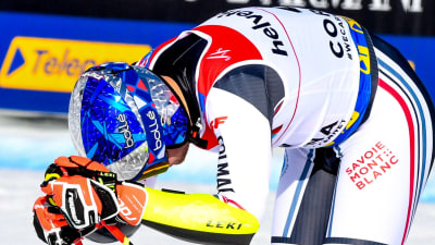 Alexis Pinturault med hjälmen på lutar sig med böjt huvud över sina skidor.