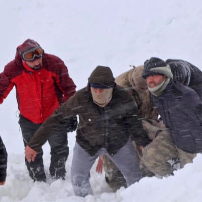 Personer går framåt i snön mitt i en snöstorm i Turkiet. 
