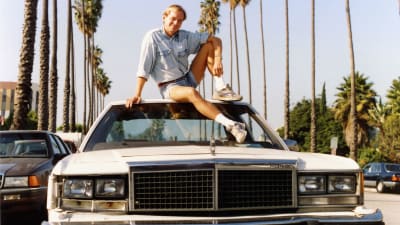 Dokumentaristen Michael Franck sitter på taket på en bil i Hollywood. 