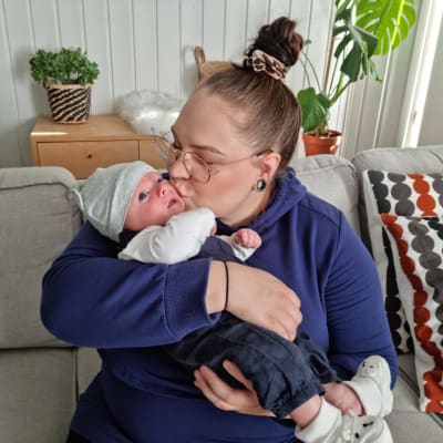 Emilia Merimaa suukottaa sylissään olevaa Nuutti-vauvaa.