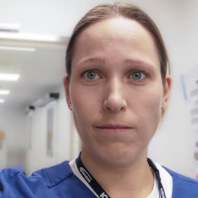 En  kvinna i läkarkläder i en vit korridor