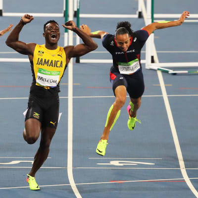 Gulklädda Omar McLeod går i mål med höjda nävar.