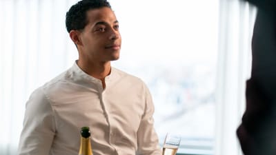 En leende man med en champagneflaska och ett glas i handen.