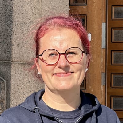 Punatukkainen nainen hymyilee kameralle.