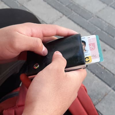 Händer som håller i plånbok med identitetshandlingar. 