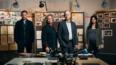 Fyra personer fotograferade i ett kontorsrum med fotografier på väggen bakom sig och teknisk utrustning framför sig på ett bord.