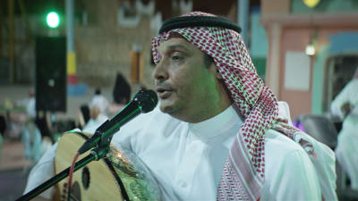 Närbild på Abdulaziz (Khalid Abdulrahim) på scen då han spelar på en oud.