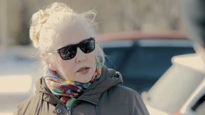 Tuula Eloranta står framför en bil och använder solglasögon.