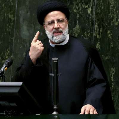 Irans president Ebrahim Raisi talar inför parlamentet framför mikrofoner.