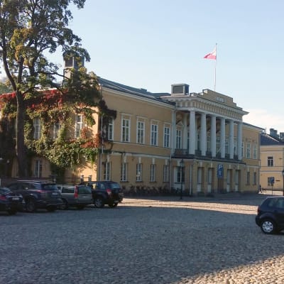 Ett gult hus med bilar parkerade framför.