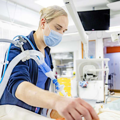 Lähihoitaja Riku Niemelä hoitaa potilasta TYKSin aikuisten teho-osastolla.