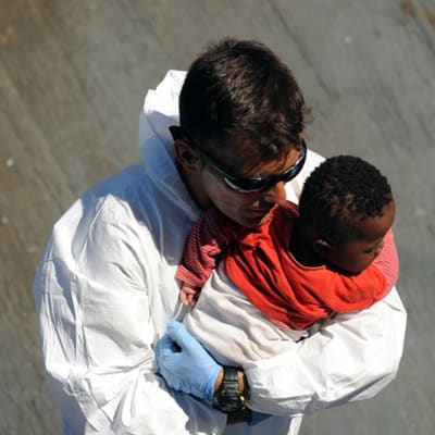 En spansk räddningsarbetare håller i en baby som räddades utanför Libyens kust den 19 juli.