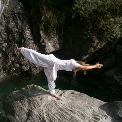 En kvinna som utför yoga på en klippa.