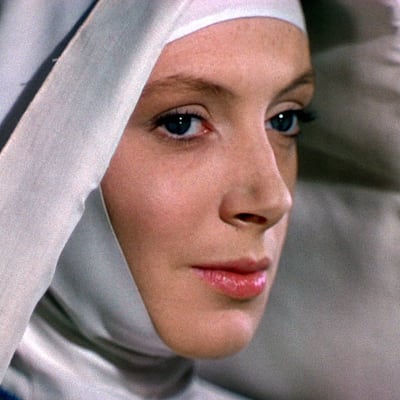 Lähikuvassa viistosti sivulta kuvattuna vienosti hymyilevä nainen (näyttelijä Deborah Kerr) valkeassa nunnan vaatteessa huiveineen, kuva elokuvasta Musta narsissi.